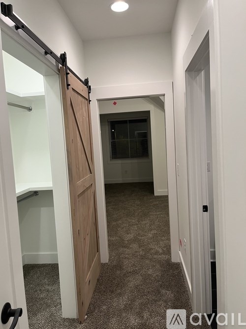 A hallway with a wooden door and a black handle.