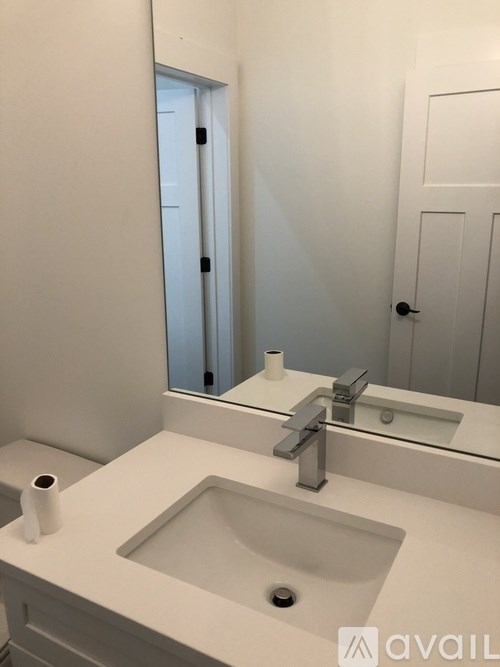 A white bathroom sink with a silver faucet and a roll of toilet paper on the counter.