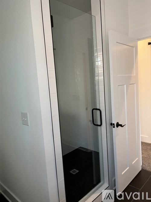 A glass door with a handle and a black mat on the floor.