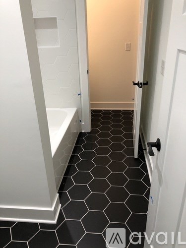 A white bathroom with a black hexagonal tile floor.