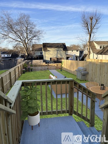 A deck with a potted plant and a table is surrounded by a wooden fence.