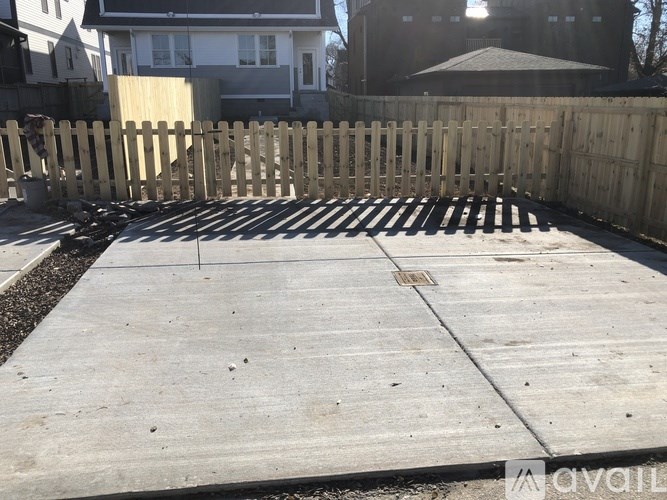 A wooden fence surrounds a concrete patio.