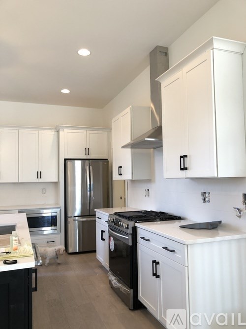 A modern kitchen with white cabinets and stainless steel appliances.