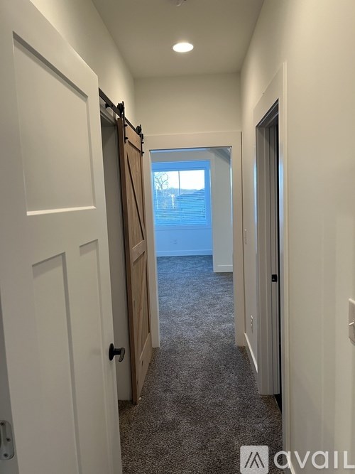 A hallway with a carpeted floor and white walls.