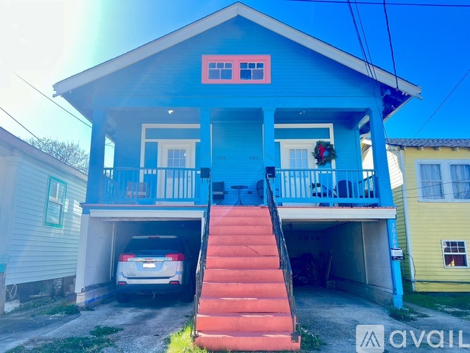 A blue house with a car in the garage.