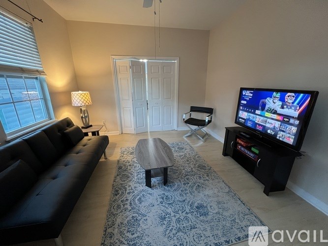 A living room with a black sofa, a coffee table, and a television on a stand.