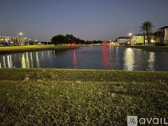 A calm body of water reflects the lights of a city at night.