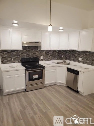 A kitchen with white cabinets and a black stove top oven.