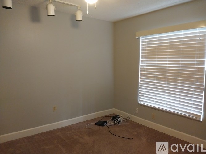 A room with a window covered by white blinds and a light on the ceiling.