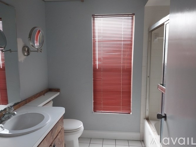 A bathroom with a toilet, sink, and red blinds.