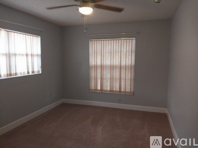A room with a ceiling fan and a window with blinds.