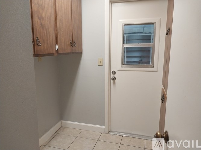 A white door with a window and a cabinet above it.