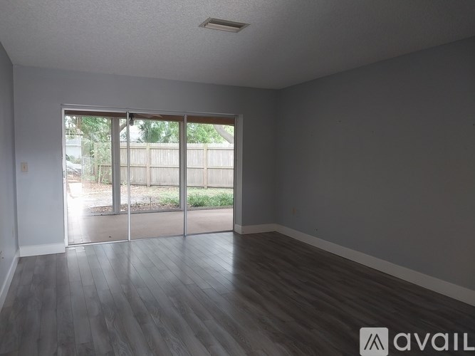 A room with wooden floors and a sliding glass door leading outside.