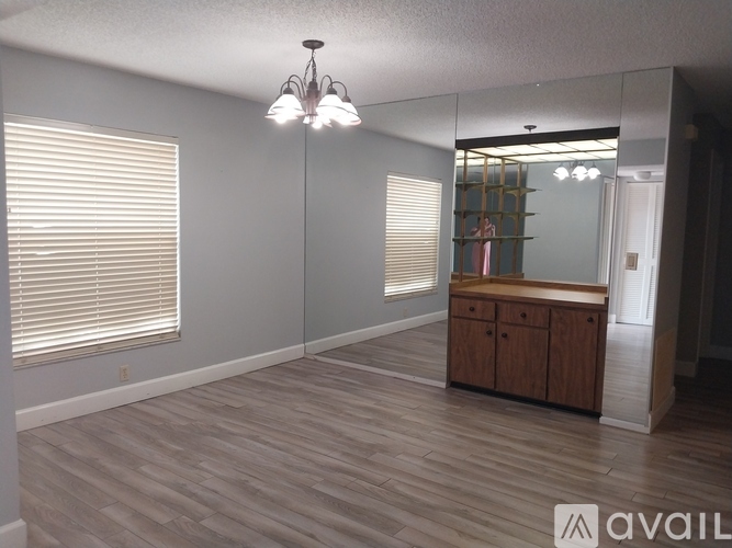 A room with wooden flooring and a cabinet under a mirror.