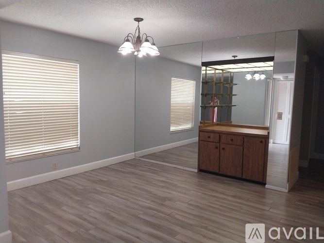 A room with wooden flooring and a cabinet under a mirror.