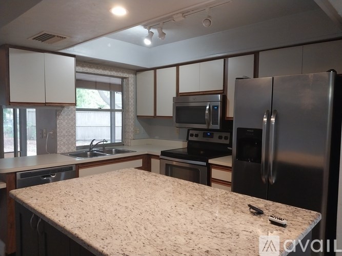 A kitchen with a granite countertop and stainless steel appliances.