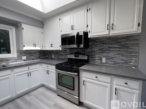 A kitchen with white cabinets and a black stove top oven.