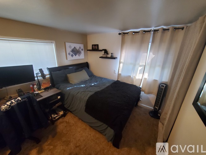 A bedroom with a bed, desk, and window.