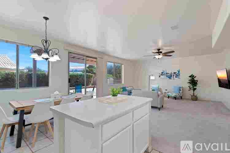 A kitchen with a white island and wooden chairs.