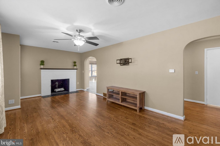 A spacious living room with a fireplace and a ceiling fan.