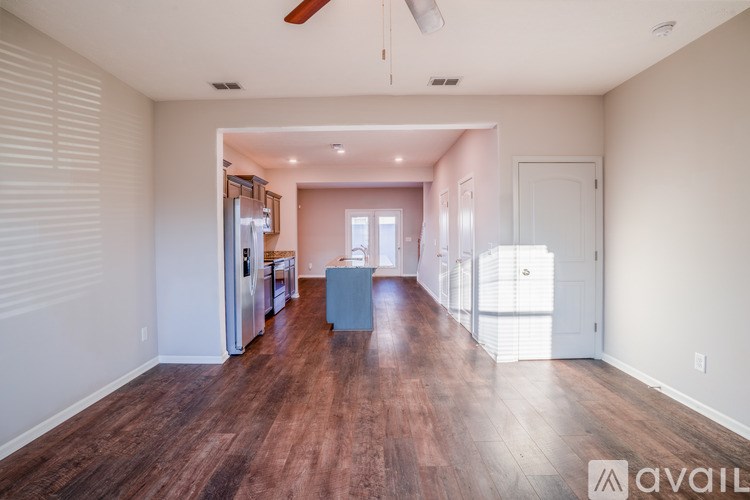 A spacious room with wooden floors and a kitchen area in the background.