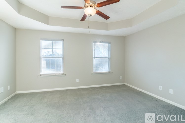 A room with a ceiling fan and two windows.
