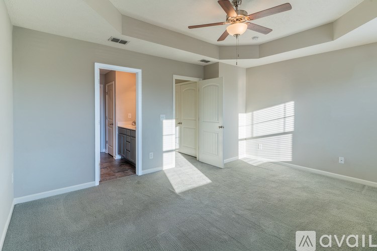A spacious living room with a ceiling fan and a rug on the floor.