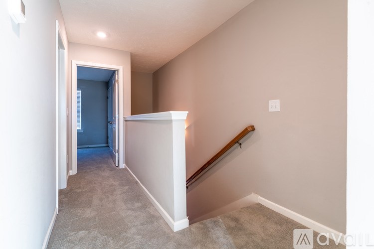 A hallway with a staircase leading to a blue room.