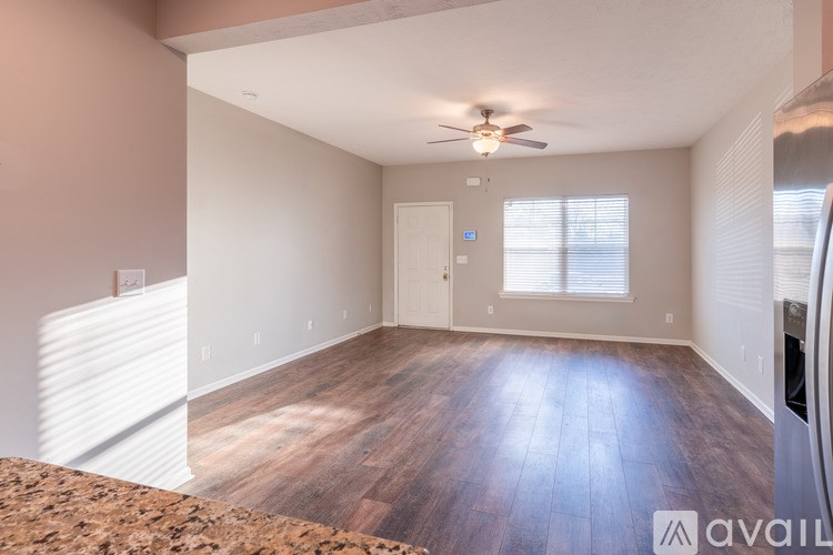 A spacious room with wooden floors and a ceiling fan.