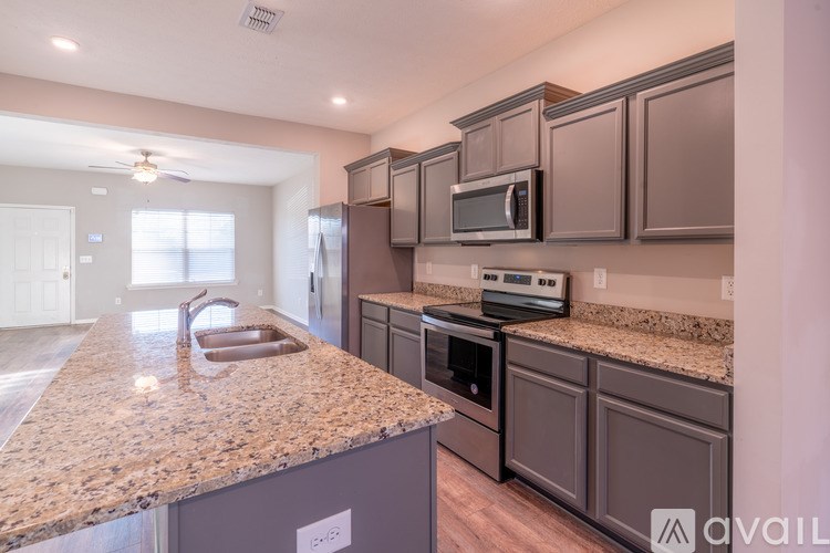 A kitchen with granite countertops and dark brown cabinets.