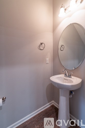 A white pedestal sink with a round mirror above it.