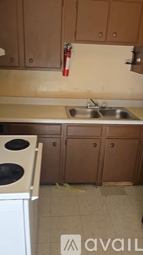 A kitchen with a white dishwasher and brown cabinets.