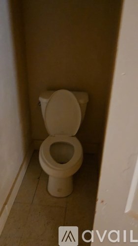 A white toilet in a small, plain bathroom.
