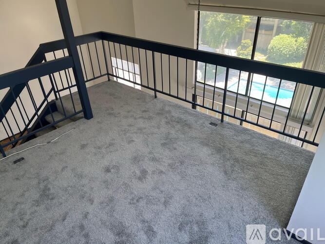 A balcony with a black railing and a grey carpet.