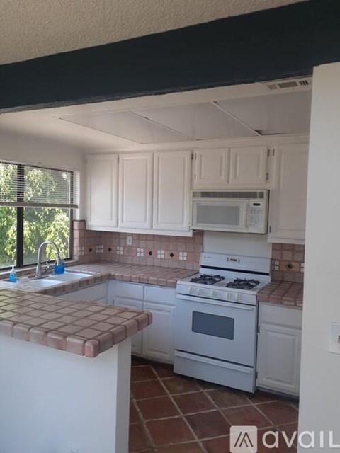 A kitchen with white cabinets and a white stove.