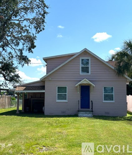 A small pink house with a blue door and a tree in front.
