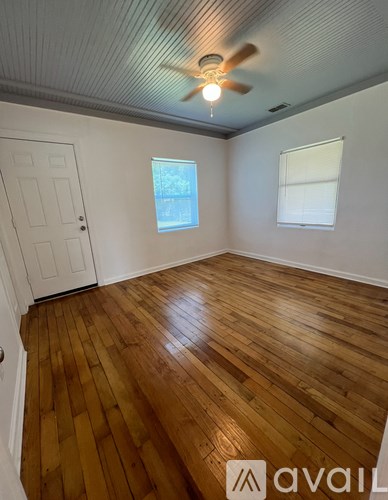 A room with wooden flooring and a ceiling fan.