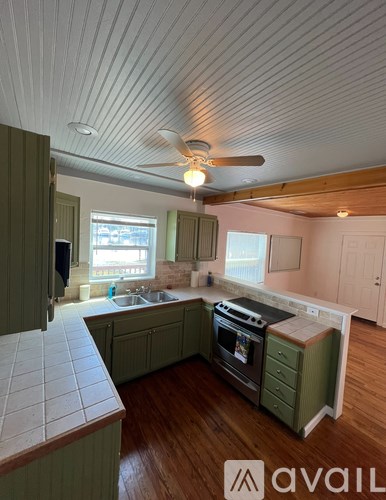 A kitchen with green cabinets and a white ceiling fan.