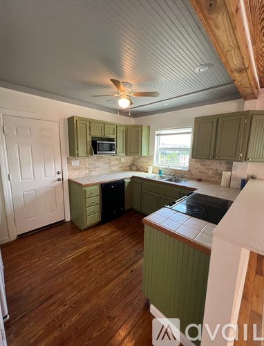 A kitchen with green cabinets and a wooden floor.