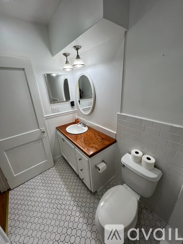 A white toilet with a wooden counter top in a bathroom.