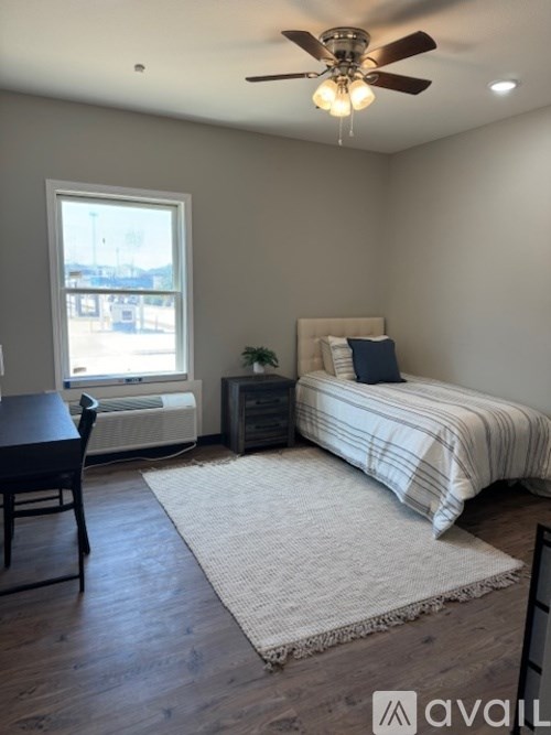 A bedroom with a bed, chair, and window.
