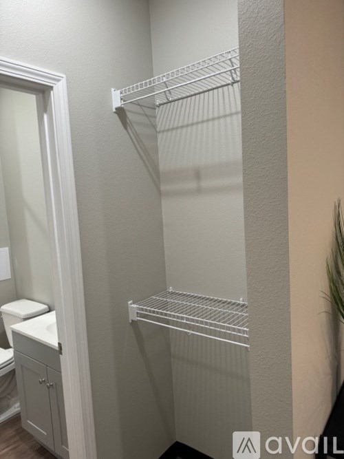 A white bathroom with a toilet and a shelf.