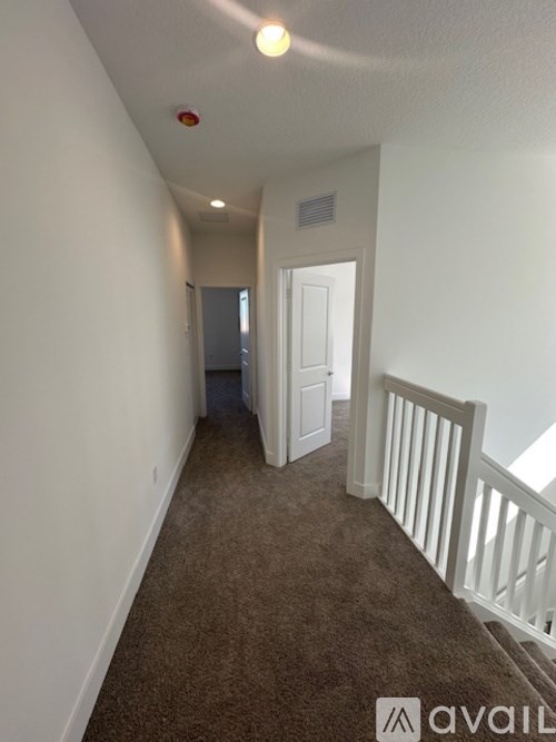A hallway with a carpeted floor and white walls.