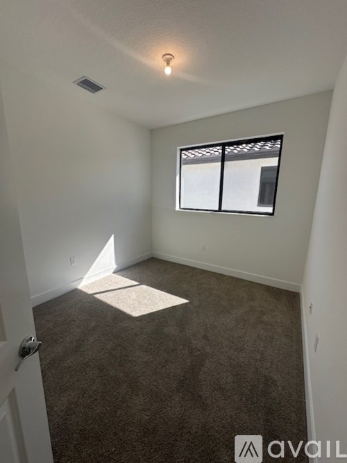 A room with a carpeted floor and a window with blinds.
