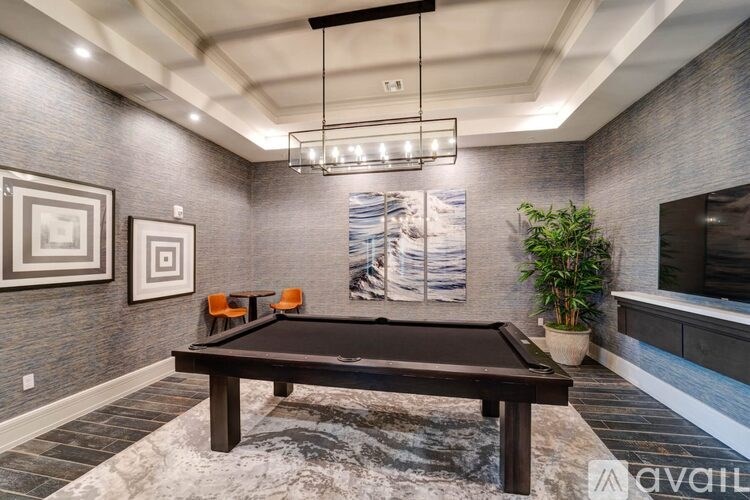 A pool table is in the middle of a room with a brick wall and a hanging light fixture.