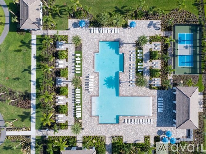 A large swimming pool surrounded by a stone patio and lush greenery.