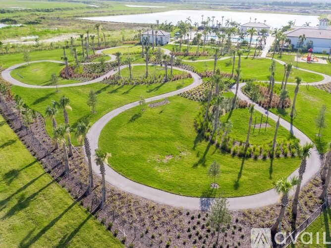 A lush green landscape with a winding path and palm trees.