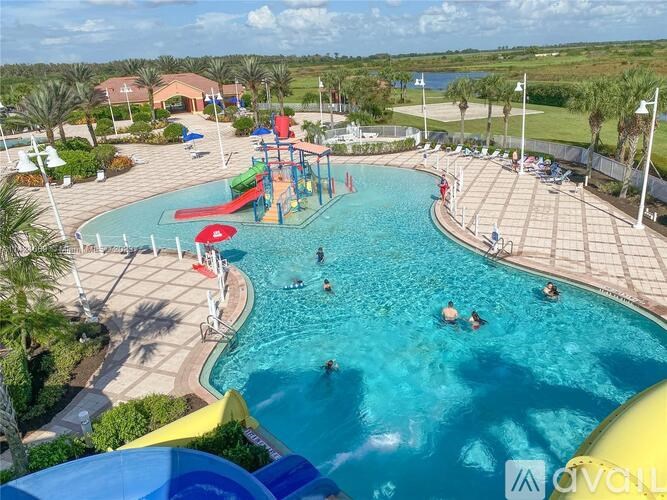 A large outdoor swimming pool with people swimming and a water slide.