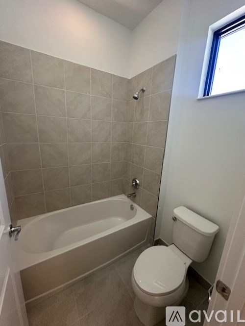 A bathroom with a toilet, tub, and tiled walls.