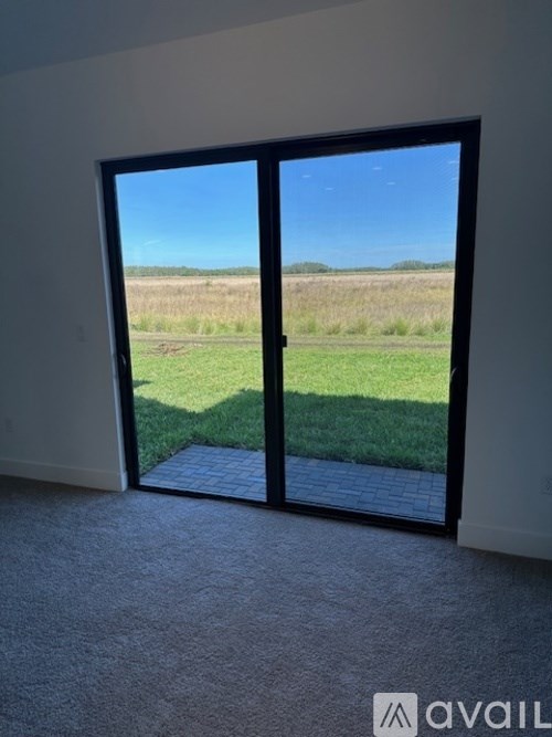 A room with a large glass door leading to a grassy field.
